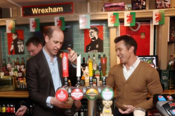 William, The Prince of Wales pours a pint with Chairman of Wrexham AFC Rob McElhenney during a visit to The Turf pub